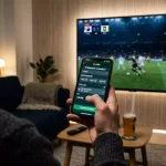 Fodboldfan følger VM-kamp live på skærm med odds der opdateres i realtid