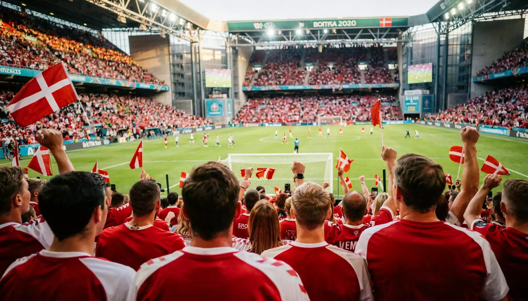 Fodboldfans i stadionets tilskuersektion med danske flag og landsholdsfarver
